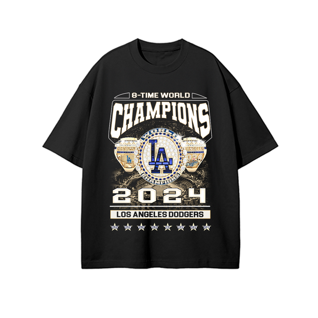 Black unisex t-shirt featuring a bold graphic of two championship rings, a large Los Angeles Dodgers “LA” emblem, and text reading “8-TIME WORLD CHAMPIONS 2024 LOS ANGELES DODGERS” with star icons along the bottom.