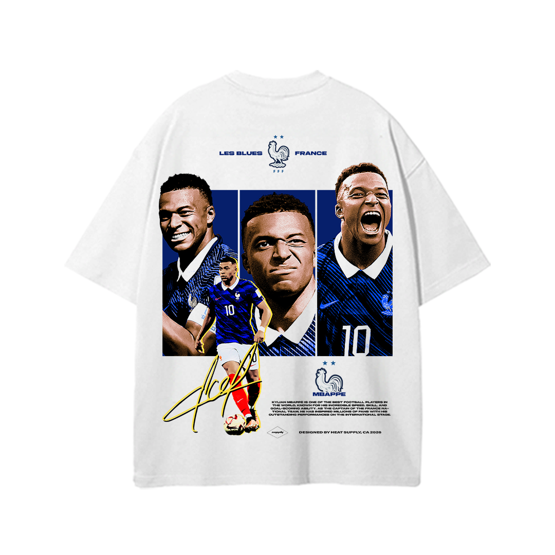 White heavyweight cotton standard fit T-shirt featuring a large back graphic of Kylian Mbappé in multiple iconic expressions and action poses wearing the France national team kit, with "LES BLEUS • FRANCE" text, French Football Federation-inspired graphics, and signature-style artwork. Vintage-inspired football streetwear design for France fans.