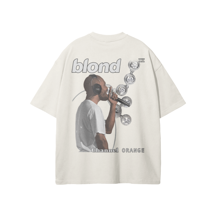 A cream-colored oversized t-shirt featuring a graphic design of Frank Ocean wearing headphones and singing into a microphone. The shirt includes the text "blond" at the top and "Channel Orange" at the bottom, with a series of album covers floating around Frank Ocean