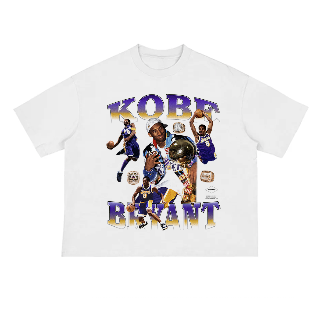 White unisex t-shirt featuring a colorful collage of Kobe Bryant in multiple action poses wearing Lakers uniforms, surrounded by championship rings and trophies, with bold purple and gold "KOBE BRYANT" text above and below the graphic.