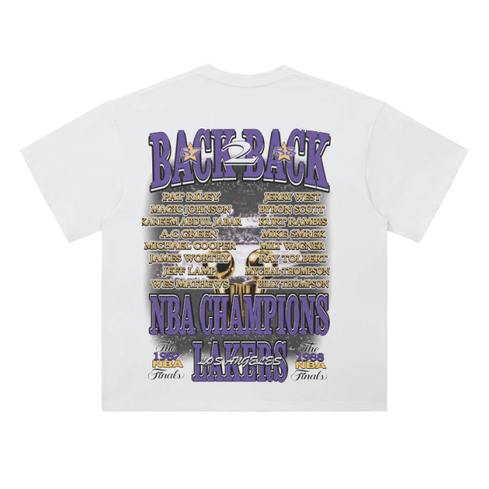 A white t-shirt featuring a retro design celebrating the Los Angeles Lakers’ back-to-back NBA championships. The back of the t-shirt displays the names of key players and coaches from the 1987 and 1988 NBA Finals, along with the phrase 'Back to Back' prominently in purple and gold. The graphic includes images of championship trophies and a basketball court
