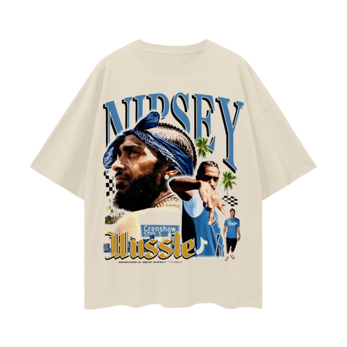A beige T-shirt featuring a graphic of Nipsey Hussle with a bandana on his head. The text "Nipsey" is written above the image in large letters, with "Hussle" below. The design includes images of Nipsey Hussle posing, palm trees, and a street sign that reads "Crenshaw 5700 S." The background has a checkered flag pattern and a few other symbolic elements.