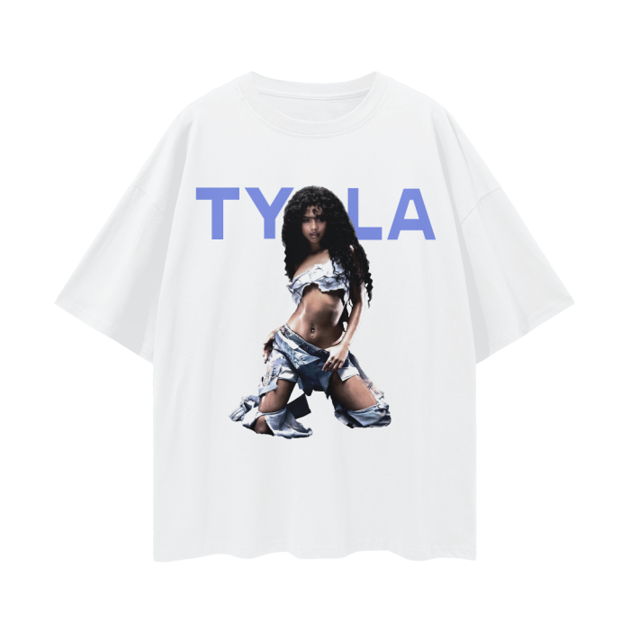 A white oversized t-shirt featuring a bold image of Tyla, a prominent music artist. The design showcases Tyla in a striking pose, wearing a denim-inspired outfit that is edgy and stylish. Above her image, the text "TYLA" is displayed in large, bold blue letters, creating a modern and eye-catching graphic.