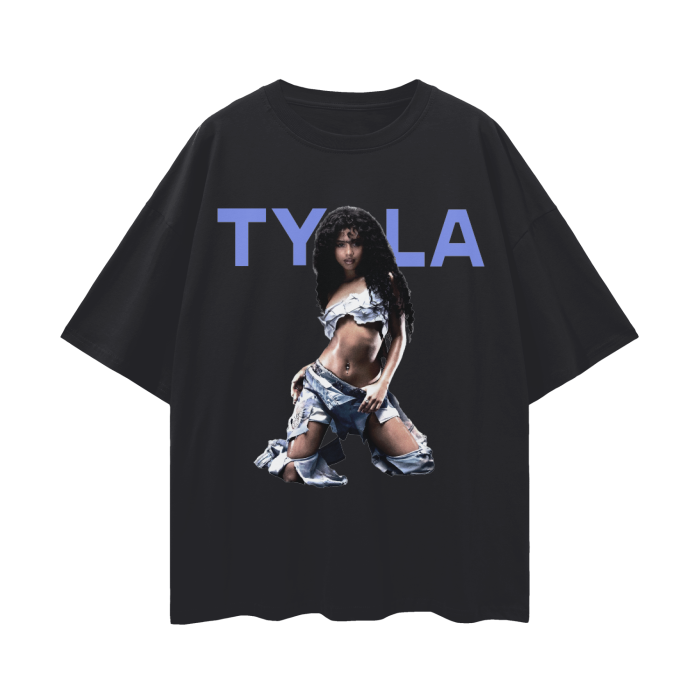 A black oversized t-shirt featuring a bold image of Tyla, a prominent music artist. The design showcases Tyla in a striking pose, wearing a denim-inspired outfit that is edgy and stylish. Above her image, the text "TYLA" is displayed in large, bold blue letters, creating a modern and eye-catching graphic.