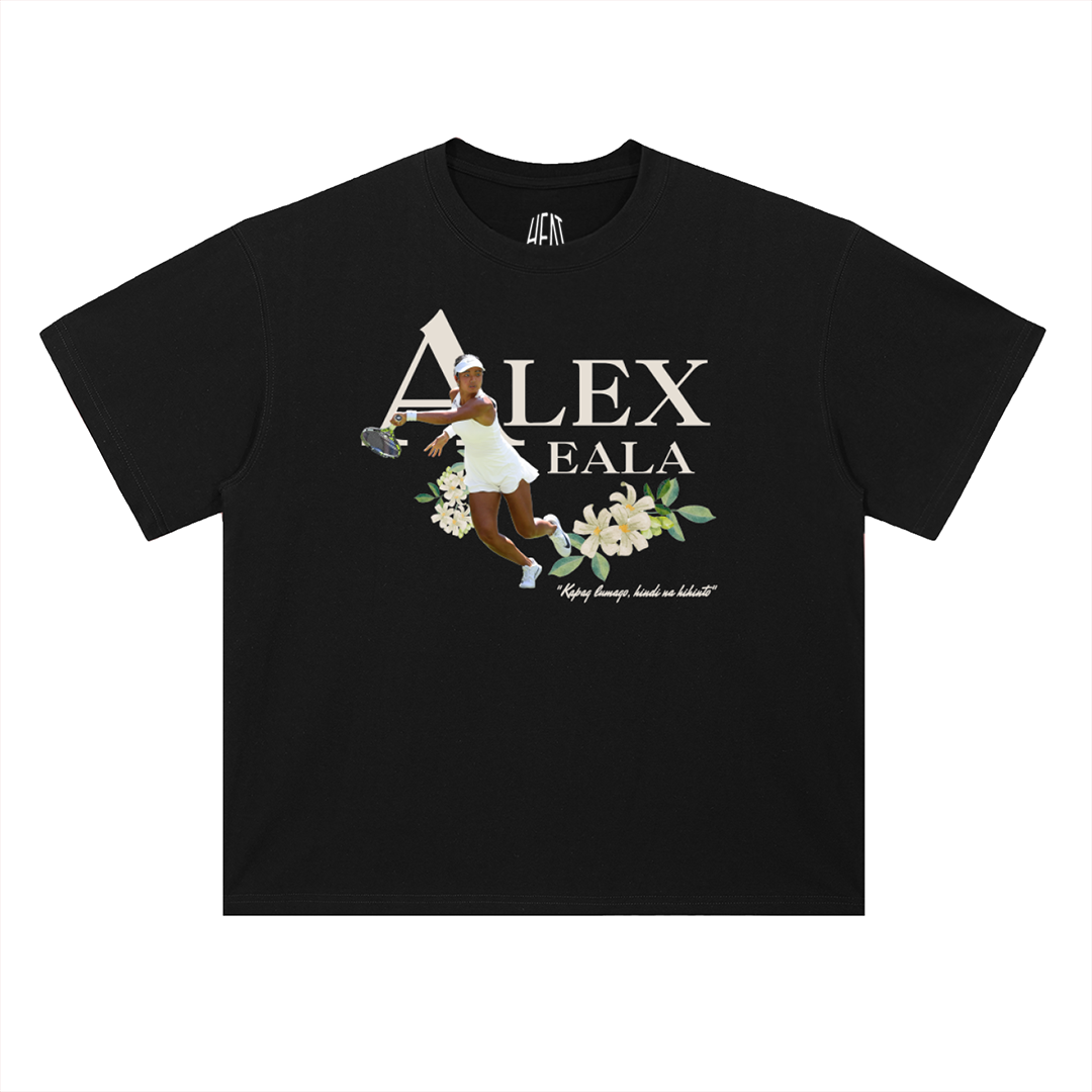 Black heavyweight cotton T-shirt featuring an action graphic of Alex Eala surrounded by elegant floral artwork with her name in large typography and an inspirational quote, creating a clean minimalist tennis-inspired streetwear design.