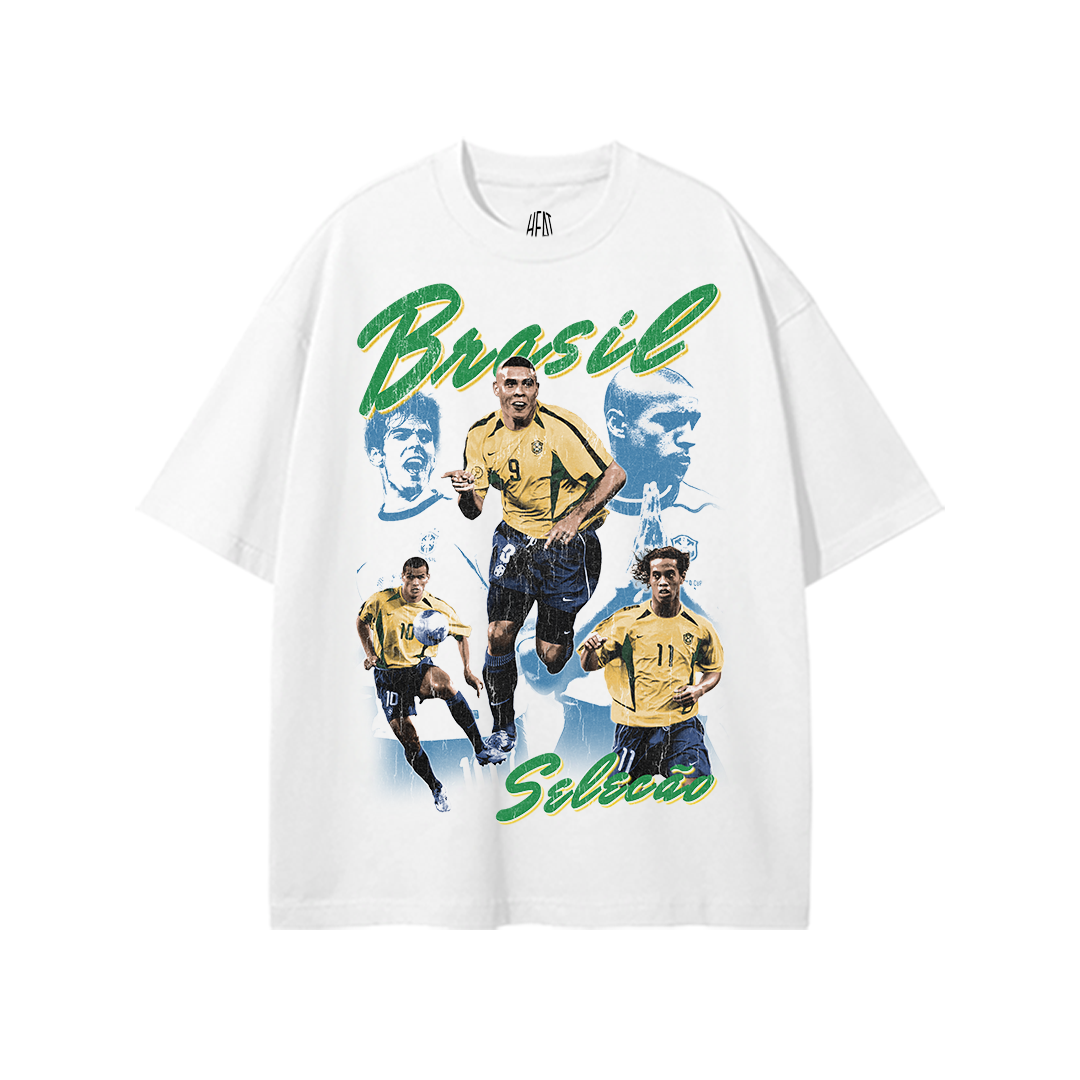 White heavyweight Brazil soccer graphic tee featuring vintage-style Brazilian national team player collage artwork with green and yellow “Brasil Seleção” typography.