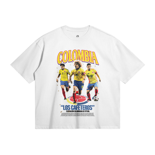Front of a white t-shirt displaying a design with the title 'Colombia - Los Cafeteros' featuring three Colombian football legends in their national team jerseys, including Carlos Valderrama, in a vintage style layout celebrating Colombian football.