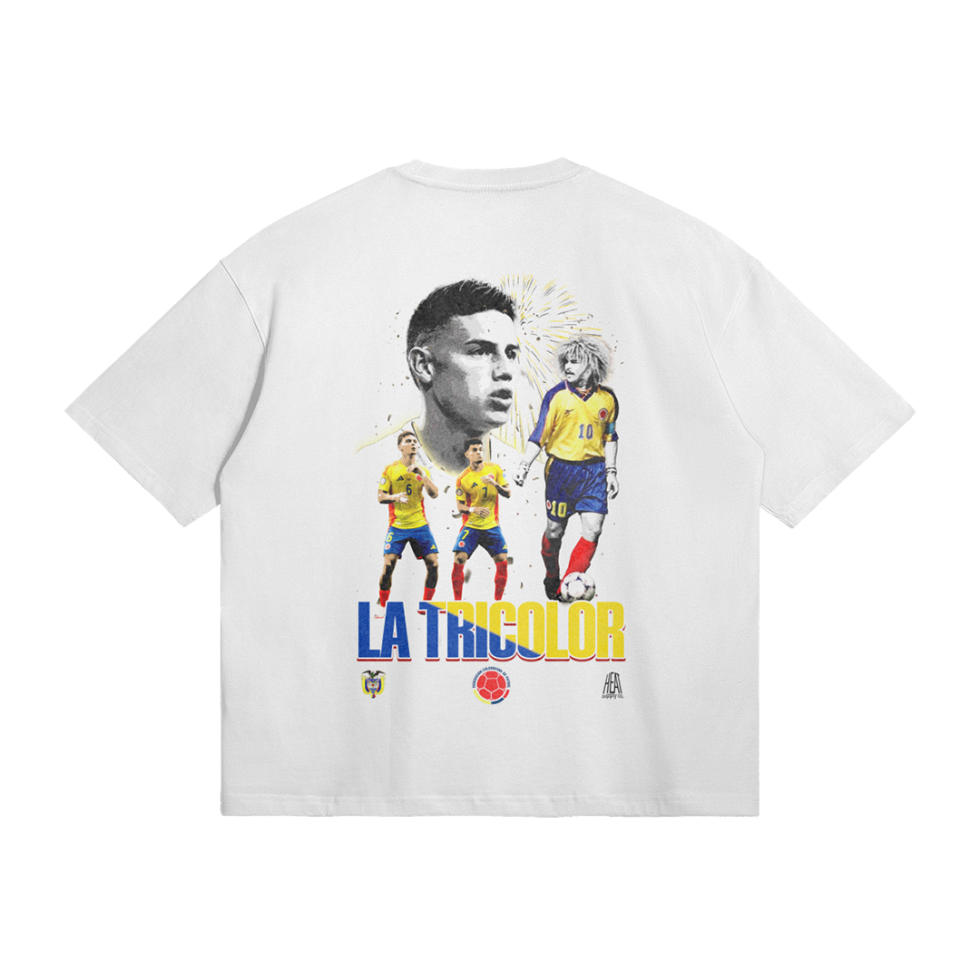 back of a white t-shirt featuring a design with the title 'La Tricolor' showcasing iconic Colombian football players, including James Rodríguez and Carlos Valderrama, in vibrant colors, celebrating Colombian football heritage.