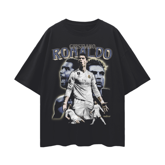 A black oversized T-shirt featuring a collage design of Cristiano Ronaldo, with the text "El Rey de Madrid" and "Máximo Goleador Histórico del Real Madrid." The design includes a large image of Ronaldo heading a ball, a smaller image of him celebrating a goal, and a series of smaller images of him playing and celebrating with his teammates.