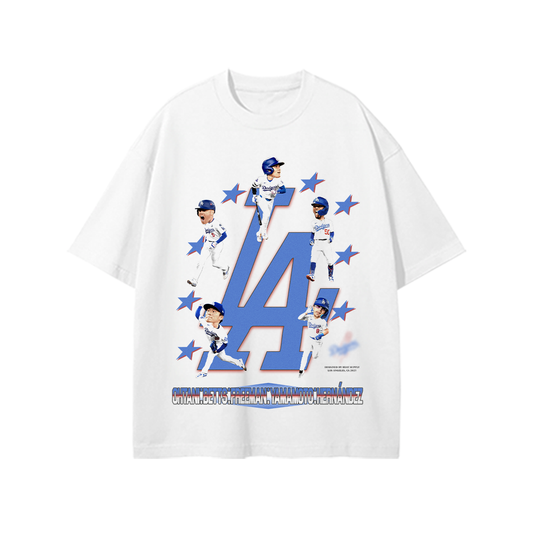 White unisex t-shirt featuring a large blue “LA” logo surrounded by bobblehead-style graphics of Dodgers players including Shohei Ohtani, Mookie Betts, and Freddie Freeman, with red stars in the background.