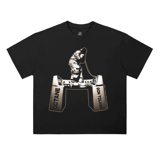Black oversized heavyweight T-shirt featuring a small centered graphic of a Don Toliver standing on recording studio equipment labeled “Octane” and “Don Toliver,” with minimal white text beneath.