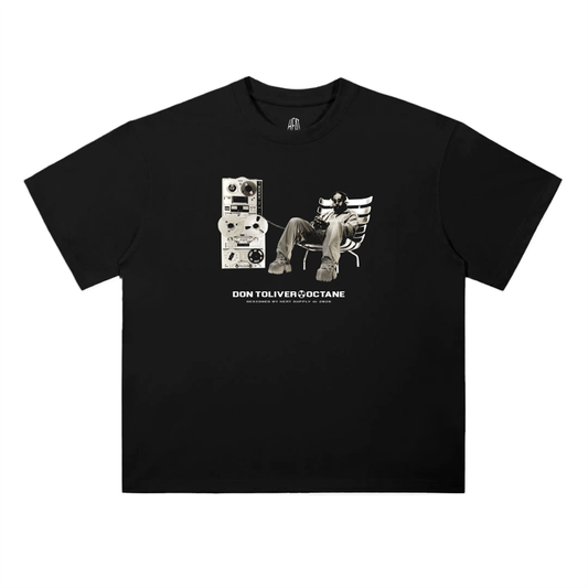Black oversized drop shoulder T-shirt featuring a minimalist “Don Toliver Octane” front graphic with a black-and-white image of Don Toliver sitting in a chair next to vintage audio equipment, with small white text printed beneath the design.