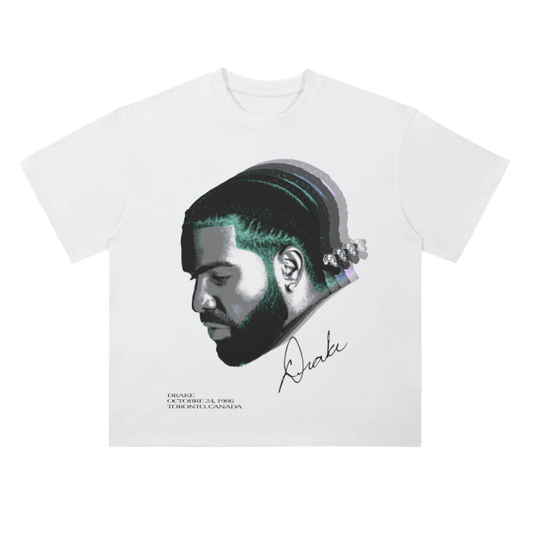 A white t-shirt featuring a minimalist design with a profile image of Drake's face in grayscale. The image is accented with a gradient effect highlighting his braided hairstyle. Below the image, the text reads "Drake: October 24, 1986, Toronto, Canada," along with Drake's signature.