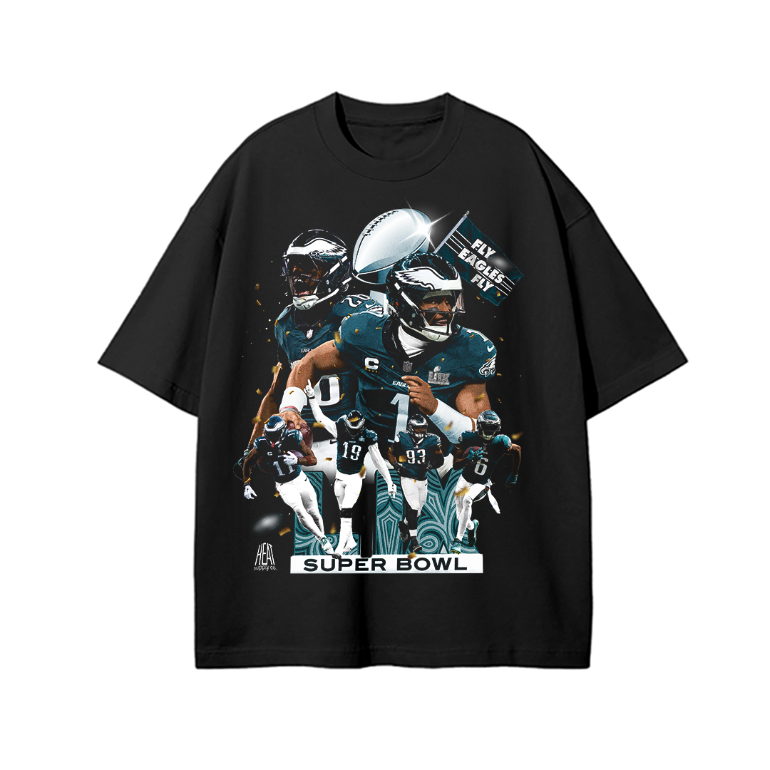 Black oversized drop-shoulder T-shirt featuring a high-energy graphic of Jalen Hurts, Saquon Barkley, and other Philadelphia Eagles players celebrating their Super Bowl win. The design includes the Lombardi Trophy, a 'Fly Eagles Fly' flag, and a bold 'Super Bowl' text at the bottom, creating a dynamic and spirited look