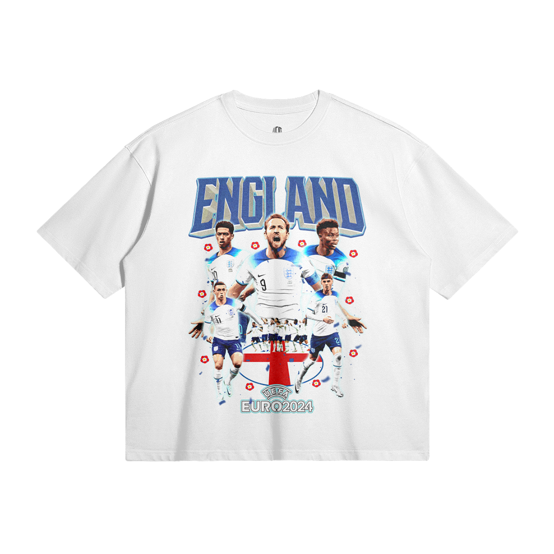 A white oversized t-shirt featuring a collage design on the front. The design showcases six England football players with the text "ENGLAND" above in bold blue letters and "EURO 2024" below the players. The players are positioned over a red and white shield with the UEFA Euro 2024 logo at the bottom.