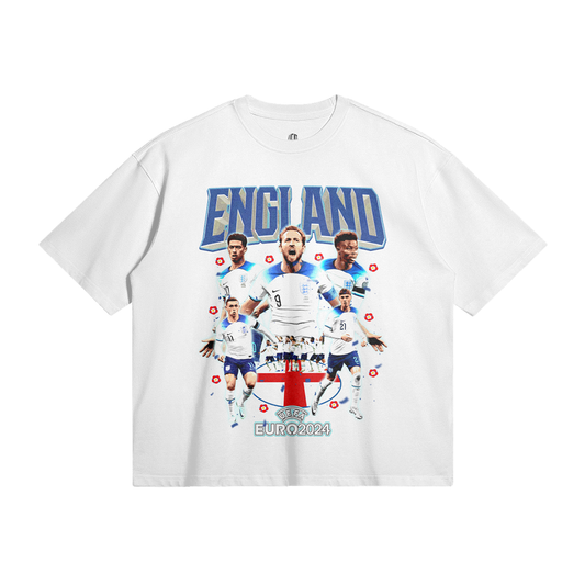 A white oversized t-shirt featuring a collage design on the front. The design showcases six England football players with the text "ENGLAND" above in bold blue letters and "EURO 2024" below the players. The players are positioned over a red and white shield with the UEFA Euro 2024 logo at the bottom.