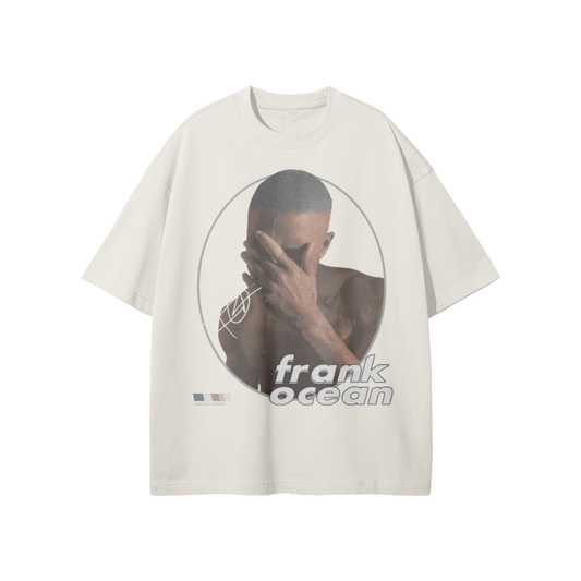 A cream-colored oversized t-shirt with a minimalist graphic design showing Frank Ocean covering his face with his hand. The design includes circular outlines around the image, with "frank ocean" written in a sleek font below.