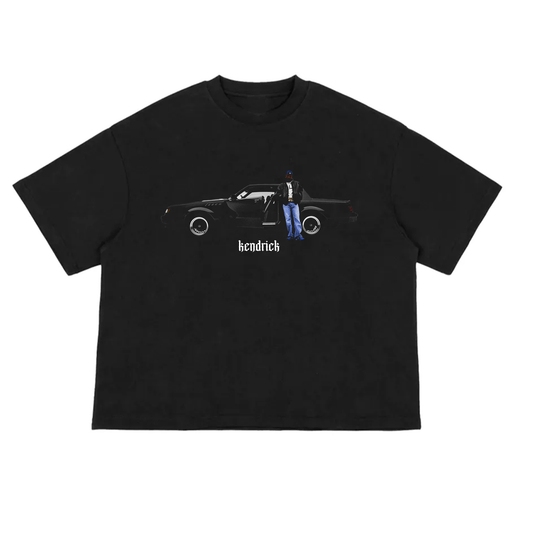 Black oversized boxy T-shirt featuring a minimalist front design of Kendrick Lamar standing beside a black Buick GNX. The image is centered on the chest with 'kendrick' written in Gothic-style font beneath, giving a clean and understated streetwear aesthetic.