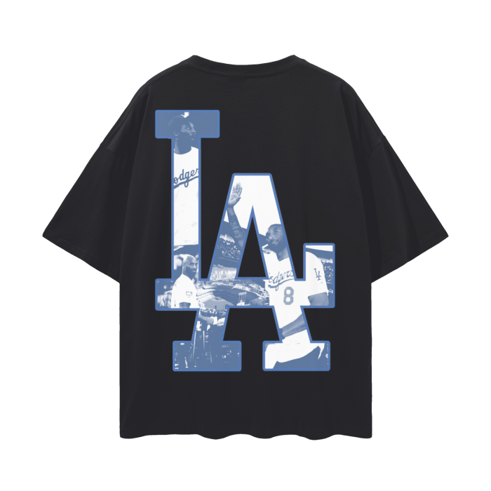 A black oversized t-shirt featuring a large "LA" logo on the back, filled with images of Kobe Bryant wearing a Dodgers jersey. The collage-style design integrates various iconic moments of Kobe in the Dodgers attire, creating a tribute to his connection with Los Angeles sports culture.