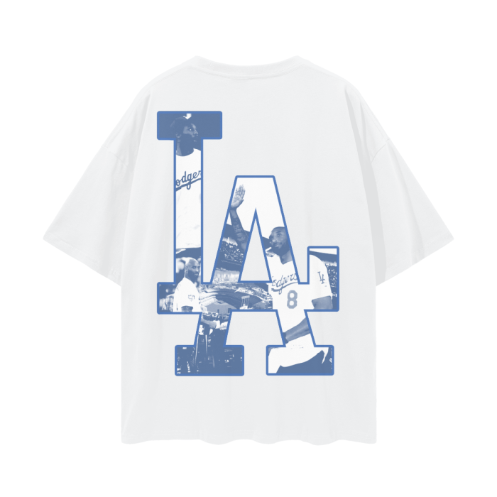 A white oversized t-shirt featuring a large "LA" logo on the back, filled with images of Kobe Bryant wearing a Dodgers jersey. The collage-style design integrates various iconic moments of Kobe in the Dodgers attire, creating a tribute to his connection with Los Angeles sports culture.