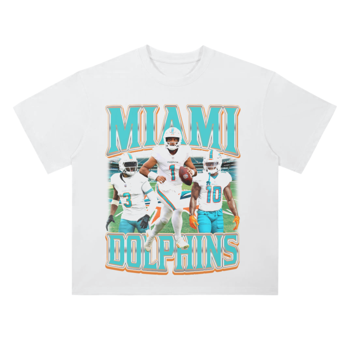 A white heavyweight drop shoulder t-shirt showcasing prominent Miami Dolphins players, including Tua Tagovailoa, in action poses on the front, with the text "MIAMI DOLPHINS" in large teal and orange letters at the top and bottom. Back