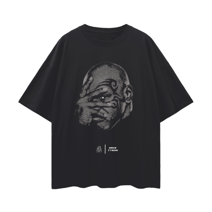 A black oversized t-shirt with a minimalist design showcasing a close-up of Mike Tyson's face, emphasizing his distinctive facial tattoo. The graphic portrays Tyson in a serious expression, with the branding of Alpha Industries and Mike Tyson displayed below.