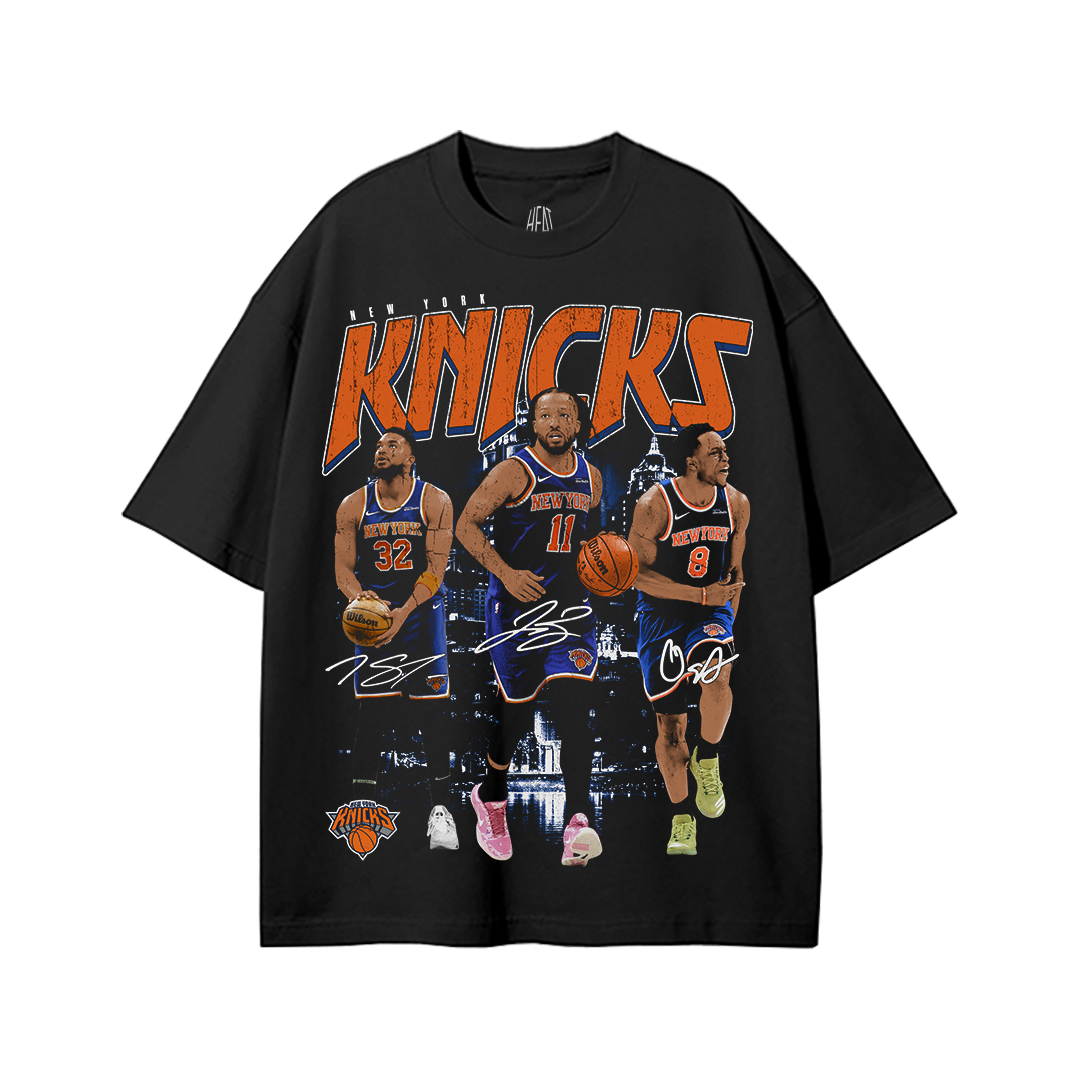 Black oversized New York Knicks graphic t-shirt featuring Jalen Brunson, Karl Anthony Towns, and OG Anunoby retro basketball artwork with multiple Knicks players, bold orange-and-blue typography, and vintage playoff-inspired streetwear graphics.