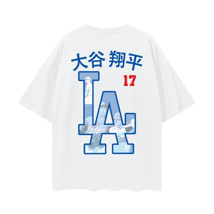 A white oversized t-shirt featuring an "LA" logo in blue, with images of Shohei Ohtani incorporated into the letters. Above the logo, "Shohei Ohtani" is written in Japanese characters along with the number 17 in red.