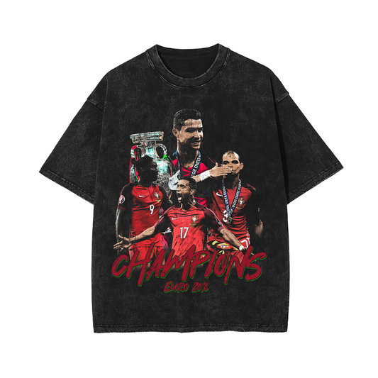A vintage acid-washed black T-shirt featuring Portugal's Euro 2016 soccer champions, including Cristiano Ronaldo. The front displays the word "Champions" in bold red text, with key players holding the trophy. The shirt has a drop-shoulder, oversized fit with a worn-in streetwear vibe.