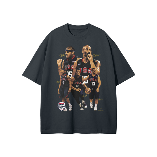 A black oversized t-shirt featuring a collage of Team USA basketball players, including Kobe Bryant, from the 2008 Beijing Olympics. The design highlights the players in action, with "USA" displayed on their jerseys and signatures scattered across the graphic.