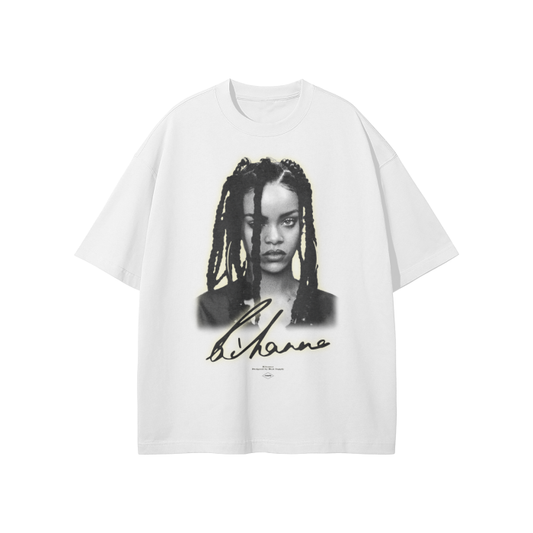 A white oversized t-shirt featuring a grayscale portrait of Rihanna with her signature below. The design has a soft glow effect around the portrait, adding a subtle highlight to the image.