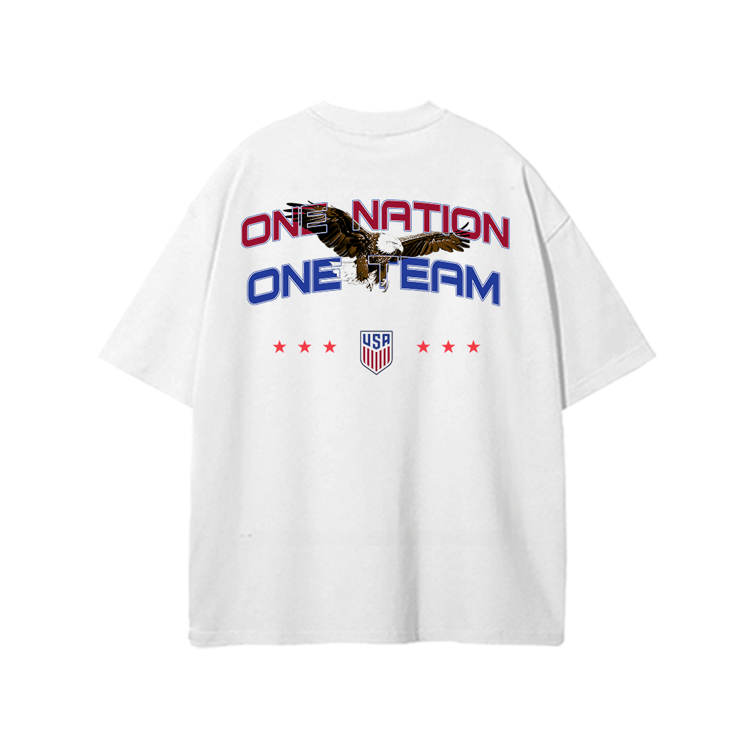 White oversized USA soccer t-shirt featuring “One Nation One Team” graphic with eagle artwork, USA crest, and patriotic red and blue typography on the back.