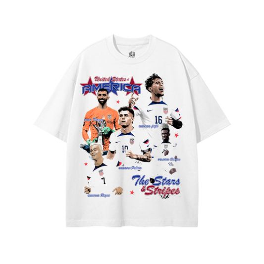 White heavyweight drop shoulder USA soccer graphic tee featuring multiple United States national team players with red and blue Americana graphics and “The Stars & Stripes” typography on the front.